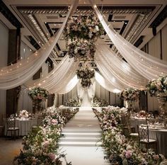 an aisle decorated with flowers and white draping for a wedding or reception venue