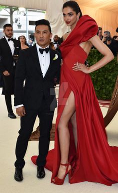 a man in a tuxedo standing next to a woman in a red dress