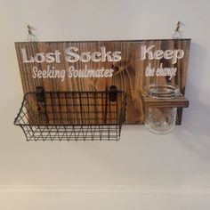 a wooden sign hanging from the side of a wall next to a wire basket and mason jar