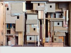 several cardboard houses are stacked on top of each other in a wooden box that is filled with wood planks