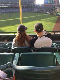 two people are sitting in the stands at a baseball game looking out into the field