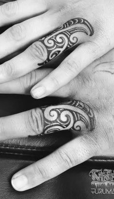 two hands with tattoos on them, one has a ring and the other has a wedding band