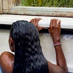 a woman in a bathtub with her hair wet and hands on the edge of the tub