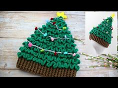 a crocheted christmas tree hat sitting on top of a wooden table next to flowers