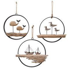 three ornaments with birds and boats hanging from the same round shape, one is made out of driftwood