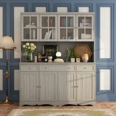 a living room with blue walls and white cupboards on top of the cabinet doors