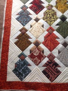 a close up of a quilt with many different colored squares on the top and bottom