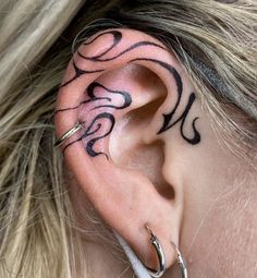 a woman's ear with tattoos on it