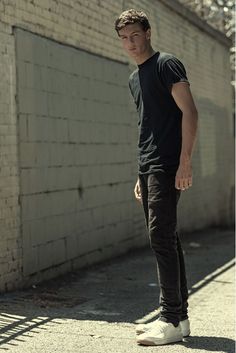 a young man standing on the street with his skateboard