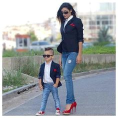 a woman standing next to a little boy on top of a pair of red shoes