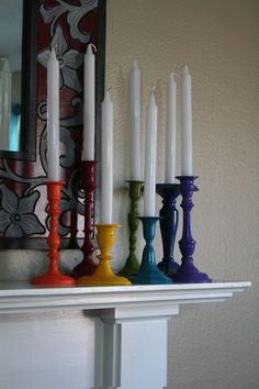 there are many different colored candles on the mantle