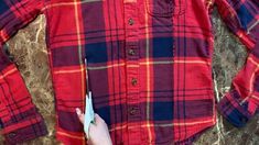 someone is holding scissors in their hand while wearing a red and blue plaid button up shirt