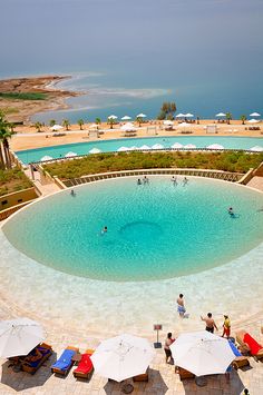 an aerial view of a pool with umbrellas and people in the water near it