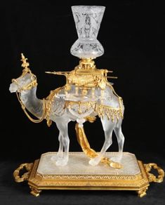 a glass and gold plated figurine with a camel on it's back