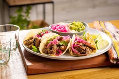 three tacos with meat, lettuce and salsa on a plate