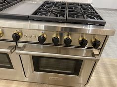 a stainless steel stove with four burners and two oven doors on the front side