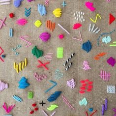 many different colored pieces of paper on a table cloth with scissors and thread spools