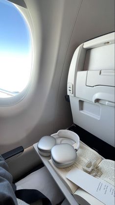 the interior of an airplane with two round windows and white trays on each side