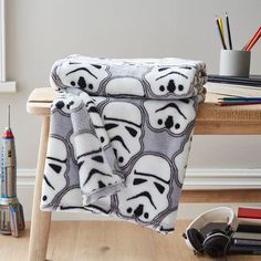 a star wars themed blanket sitting on top of a wooden bench next to pencils and markers