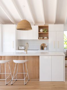 two white stools in front of a kitchen island with wooden countertops and cabinets