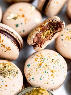 there are many macaroons with gold flecks on them and one has a bite taken out