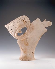 a ceramic sculpture of a bird with its mouth open and eyes wide open, sitting on a white surface