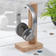 the headphones are on display in front of a potted plant and wooden stand