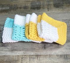 four crocheted dishcloths sitting on top of a wooden table