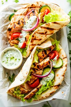 two chicken pita sandwiches with lettuce, tomato and cucumber sauce