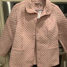 a pink quilted jacket hanging on a rack