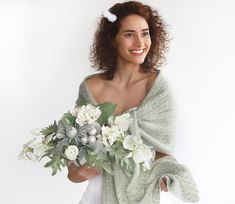 a woman holding a bouquet of flowers in her hand and smiling at the camera while standing against a white background