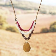 the necklaces are made with beads, wood and other things on display in front of an open field