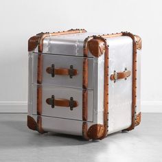 an old suitcase is sitting on the floor in front of a white wall with two drawers