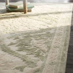 a white rug with an intricate design on the floor next to a table and chair