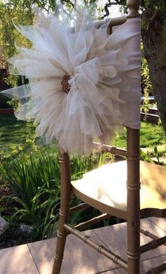 a chair with a flower on it sitting in front of a tree and some grass