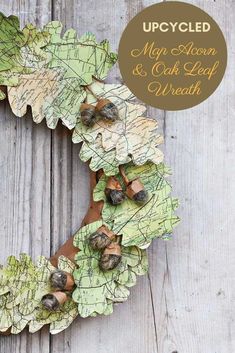 an upcycled wreath with leaves and acorns is displayed on a wooden surface