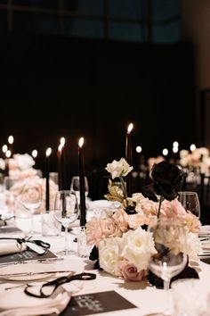 the table is set with white and pink flowers, black candles, and menus