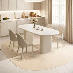 a white kitchen with an oval dining table and four chairs in the center, along with beige curtains on the windows