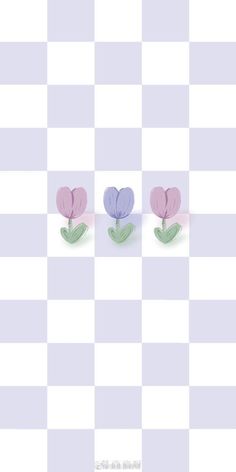 three paper flowers sitting on top of a checkered tablecloth with the same pattern