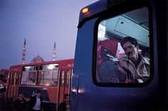 a man sitting in the passenger seat of a bus looking out the window at other people