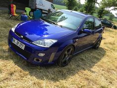 a blue car parked on top of a grass covered field