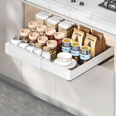 an open drawer in a kitchen filled with spices and other food items next to a sink