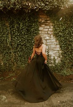 the back of a woman's dress as she stands in front of a brick wall