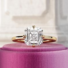 a diamond ring sitting on top of a pink box