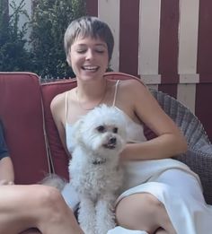 a woman sitting on a chair with a white dog