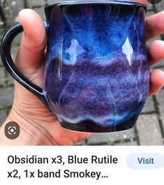 a hand holding a blue and purple coffee cup