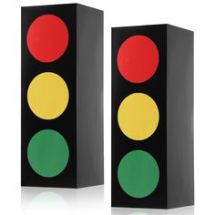 two traffic lights sitting next to each other on a white surface and one is red, the other green