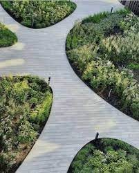 an outdoor walkway surrounded by green plants and bushes in the shape of curved circles on top of each other