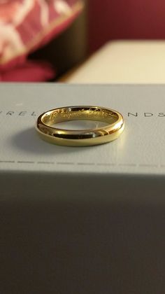 a gold wedding ring sitting on top of a box