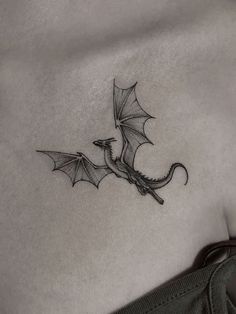 a small dragon tattoo on the back of a woman's left side ribcage